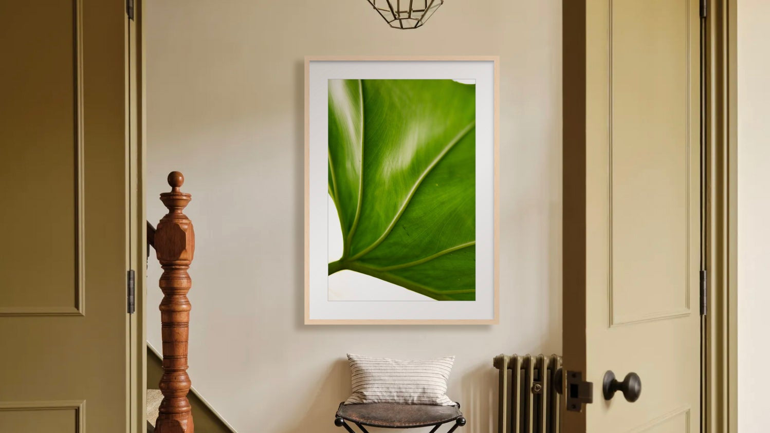 Room with a 'Ape green leaf framed photograph on the wall, wooden staircase, and skateboard.